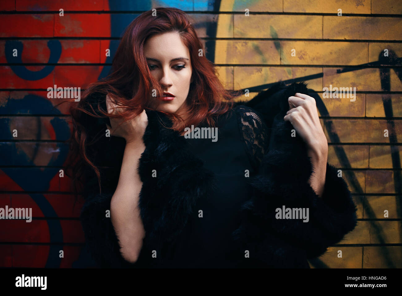 Schöne rote kurzhaarige Frau gegen Graffiti. Street-fashion Stockfoto