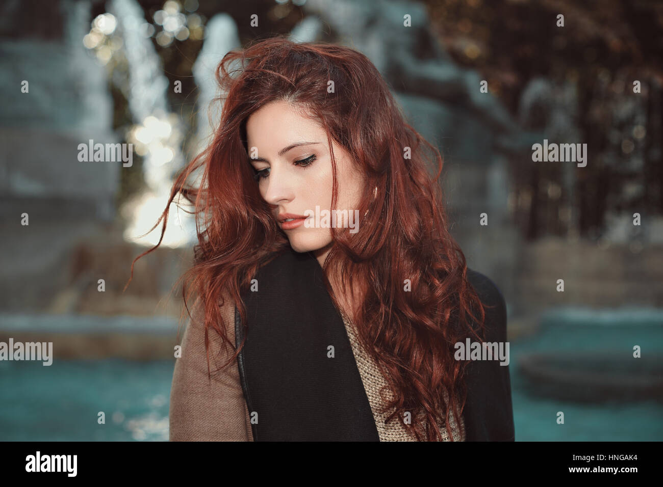 Schöne junge Frau mit roten Haaren. Brunnen-Hintergrund Stockfoto