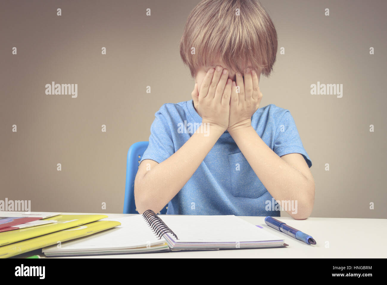 Müde, traurig Kind Hausaufgaben zu Hause. Der junge satt und bedeckt sein Gesicht mit den Händen. Bildung, Schule, Schwierigkeiten Lernkonzept Stockfoto