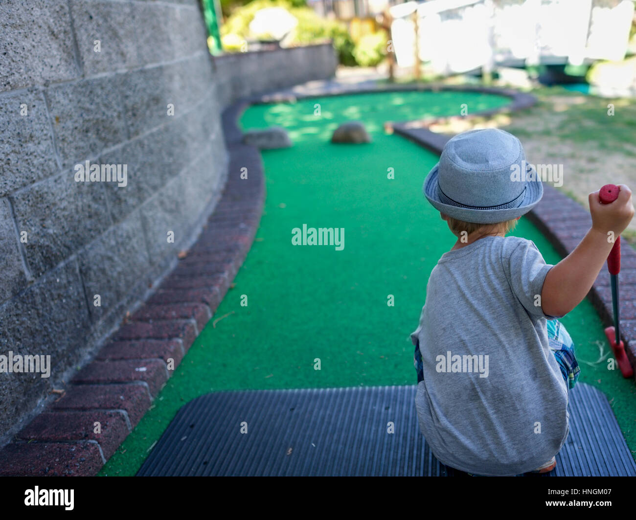 Kleiner Junge Vorschulkind Golfspielen Minigolf oder verrückt auf eine Minigolf-Anlage im Sommer Stockfoto