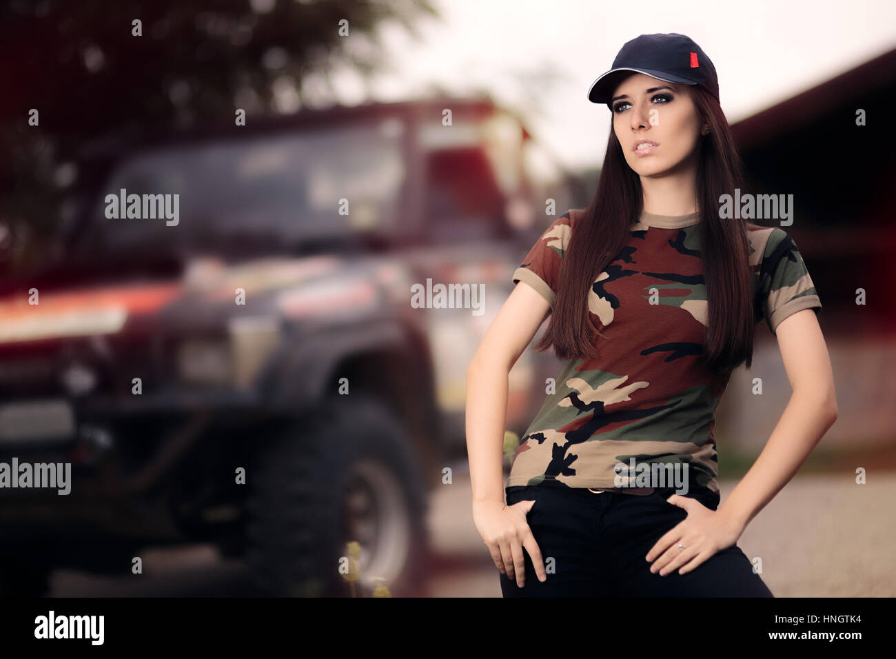 Fahrerin im Army-Outfit neben einem Off-Road Auto Stockfoto