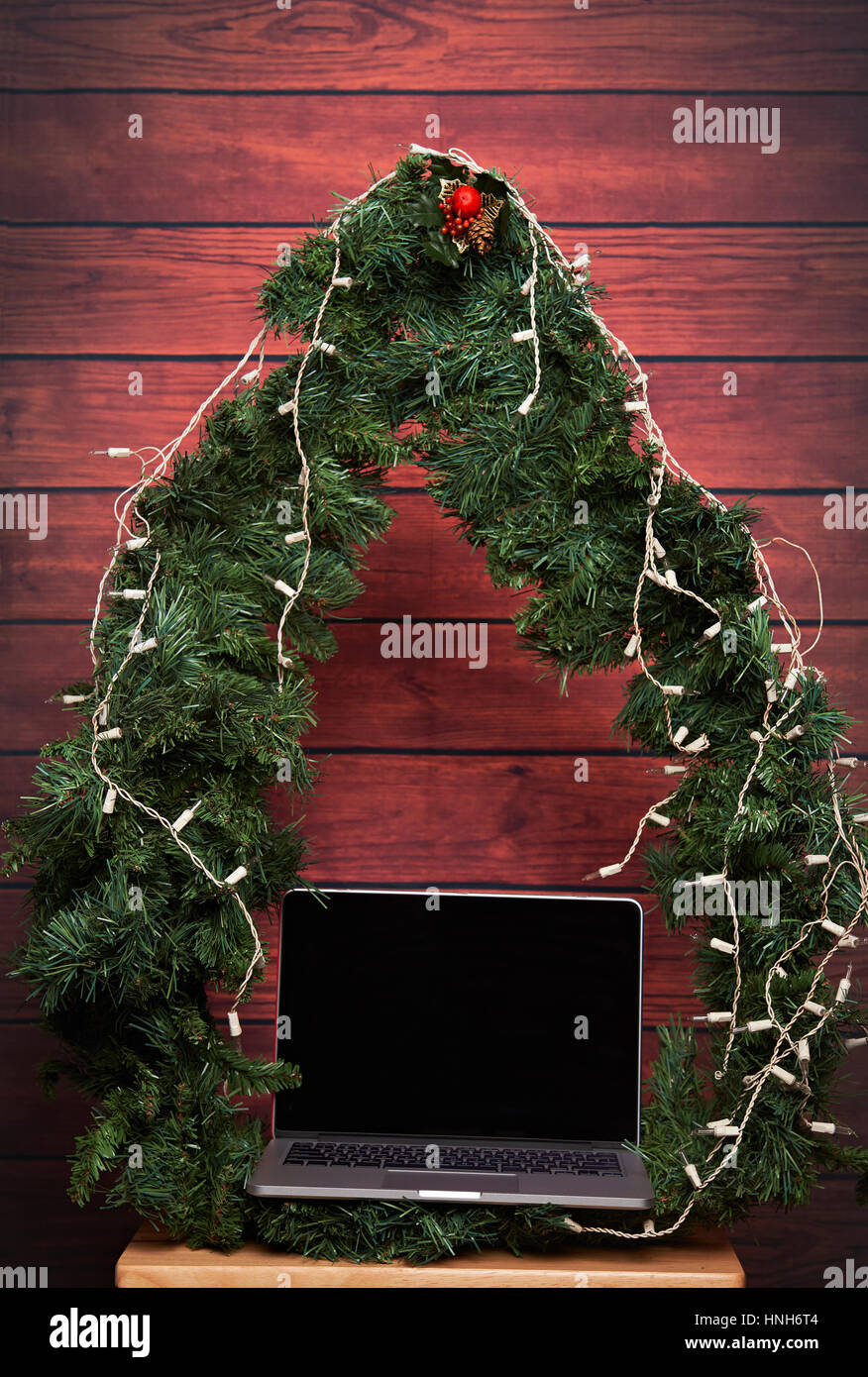 Laptop als Geschenk zu Weihnachten auf hölzernen Hintergrund. Notebook im Baum runder Rahmen Stockfoto