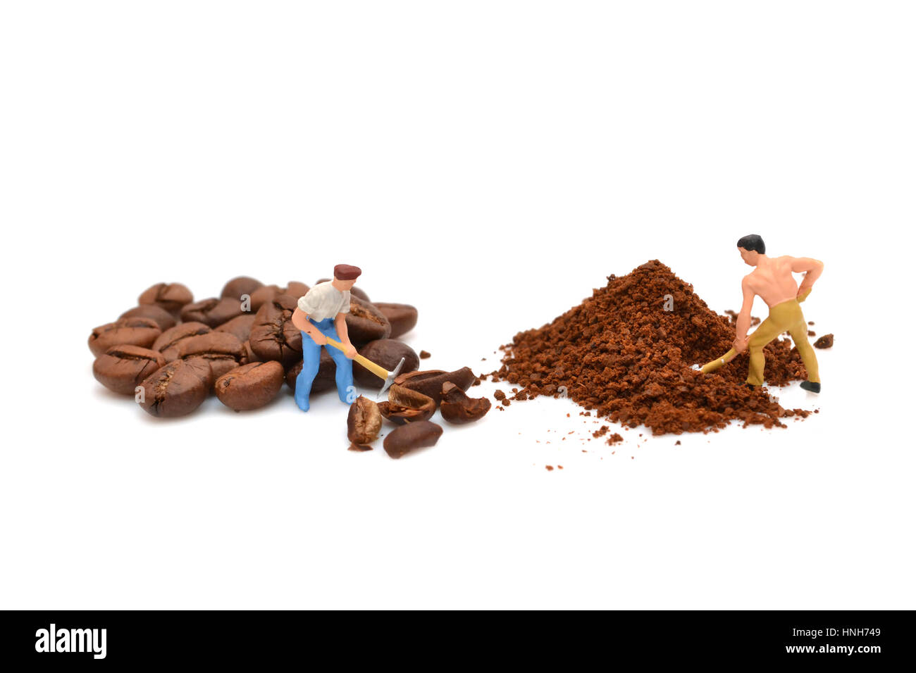 Miniatur-Menschen Kaffeepulver. Kleine Leute brechen Kaffeebohnen. Gemahlenen Kaffee. Makro. Figuren von Menschen. Statuette. Handvoll Kaffee Stockfoto