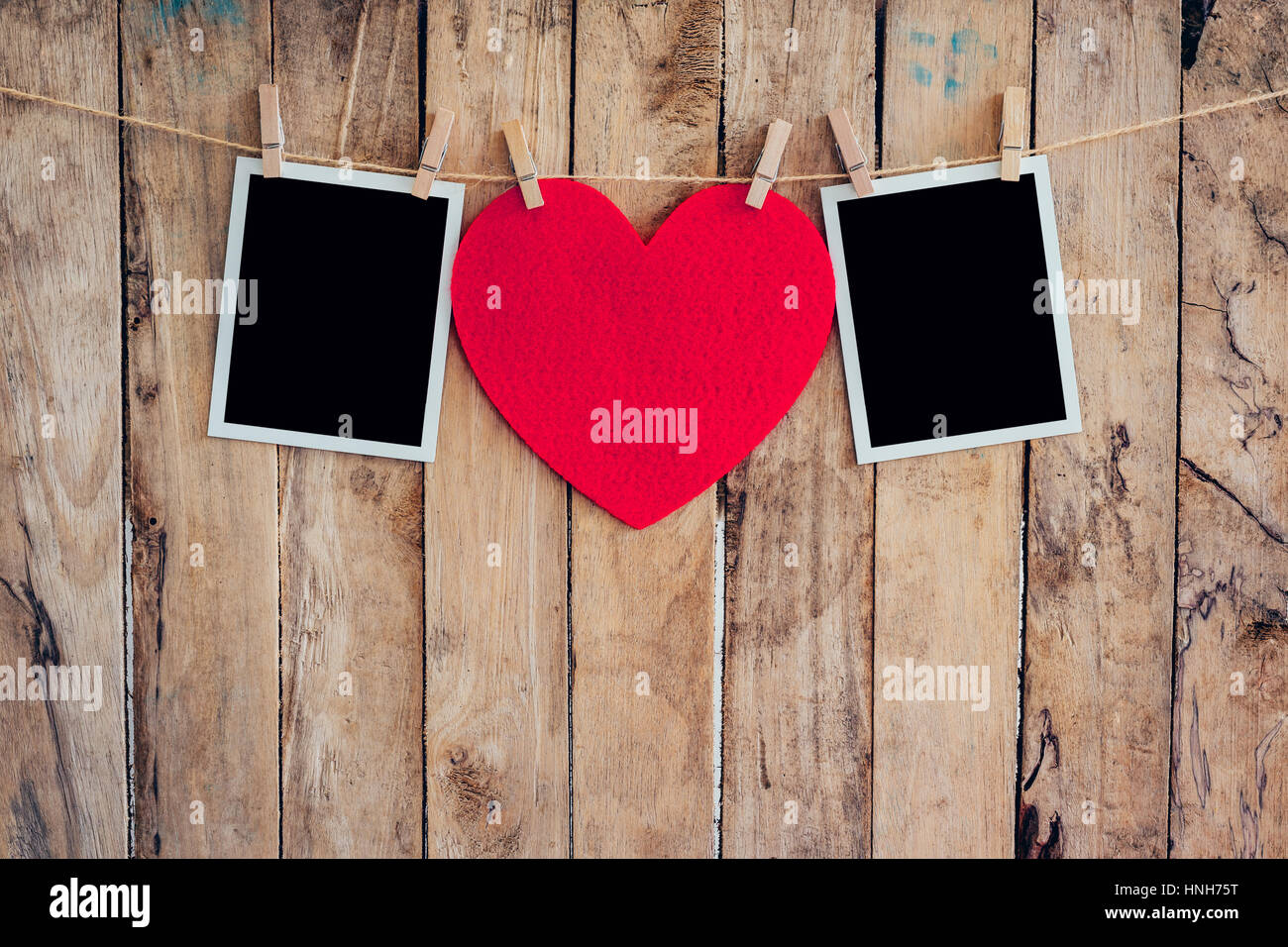 Rotes Herz und zwei Bilderrahmen hängen, Wäscheleine Seil mit hölzernen Hintergrund. Stockfoto