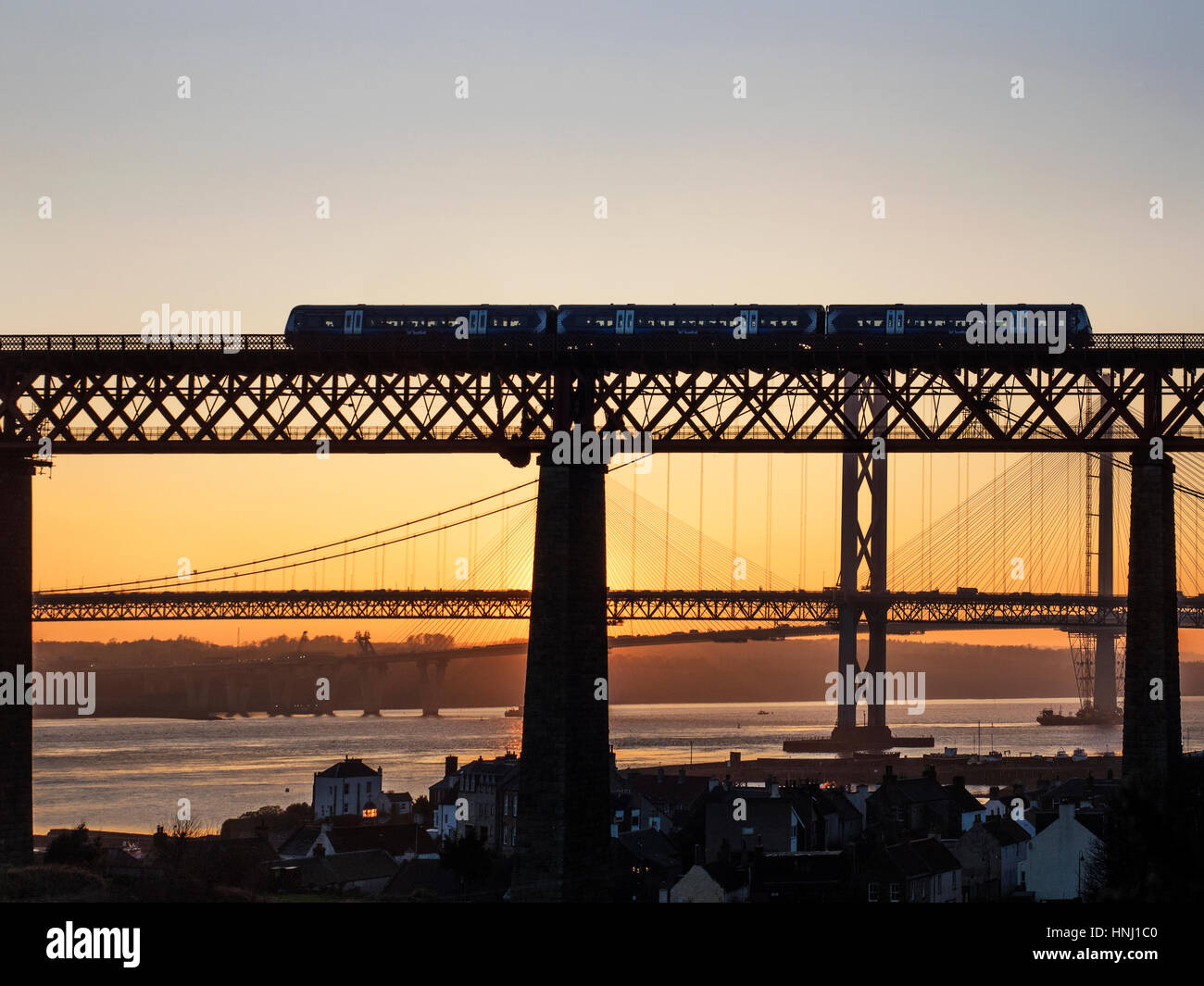 Personenzug der Forth-Brücke mit den Straßenbrücken hinter bei Sonnenuntergang North Queensferry Fife Schottland Stockfoto