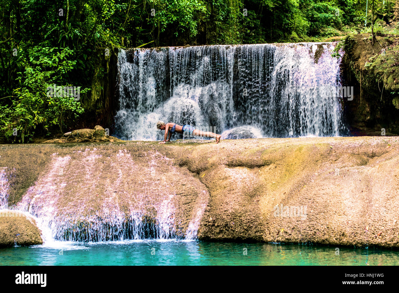 Frau tut Push Ups vor Wasserfall in Jamaika. Stockfoto