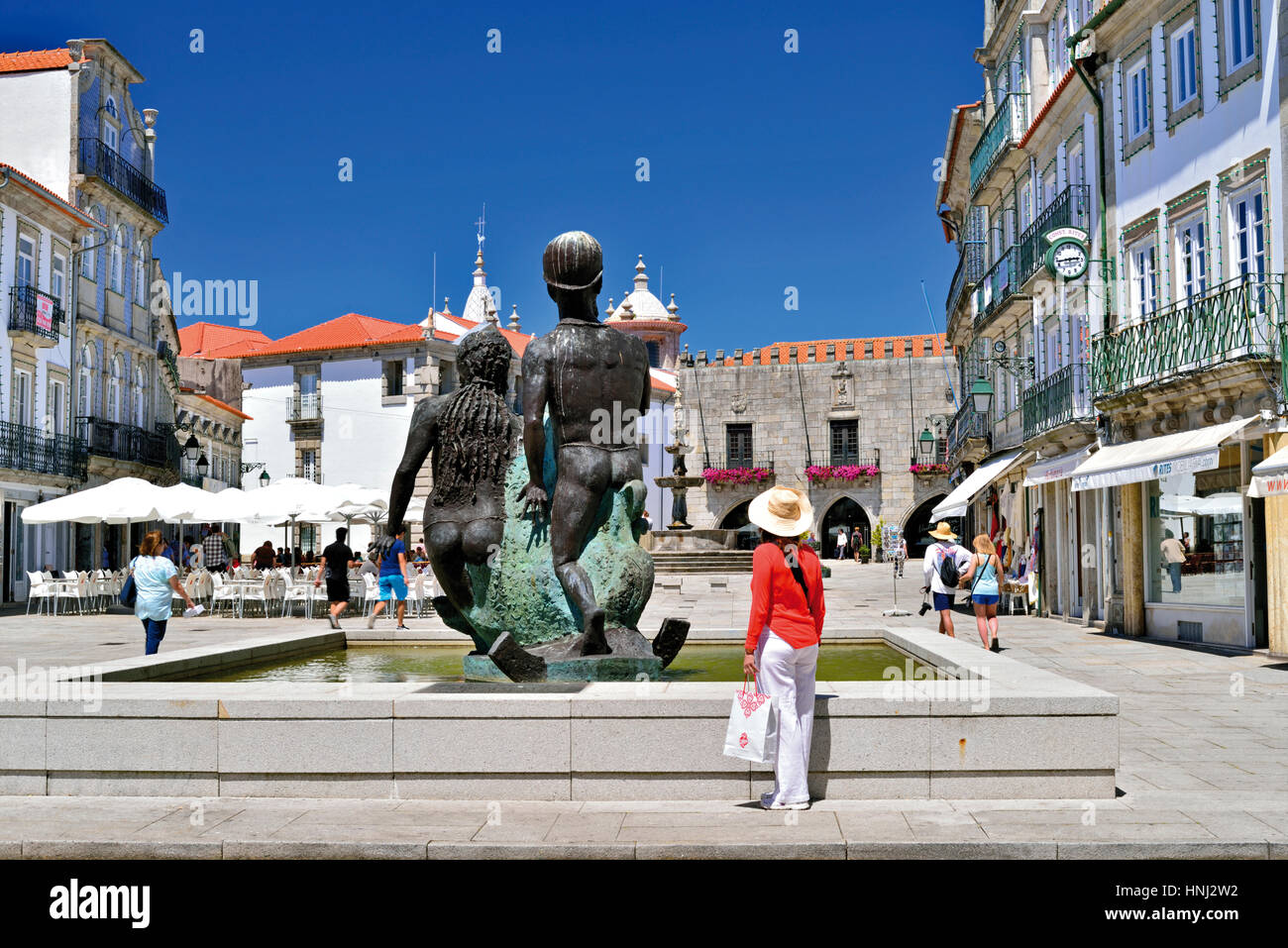 Portugal: Frau mit Hut und Einkaufstasche am zentralen Brunnen im historischen Zentrum von Viana do Castelo Stockfoto