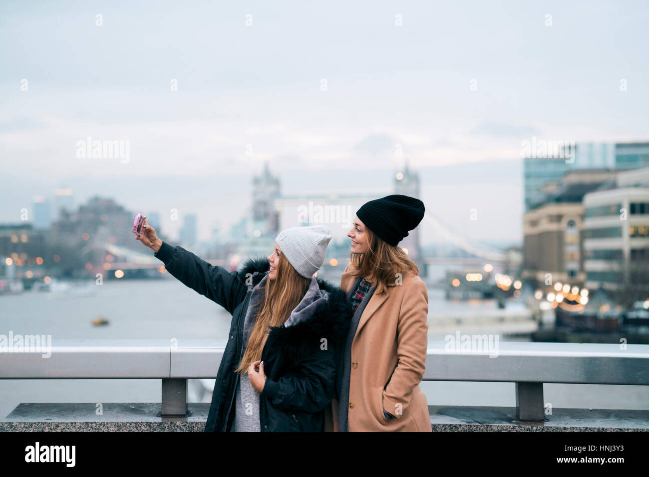 Freunde nehmen Selfie stehend gegen Fluss in der Stadt gegen die Tower bridge Stockfoto