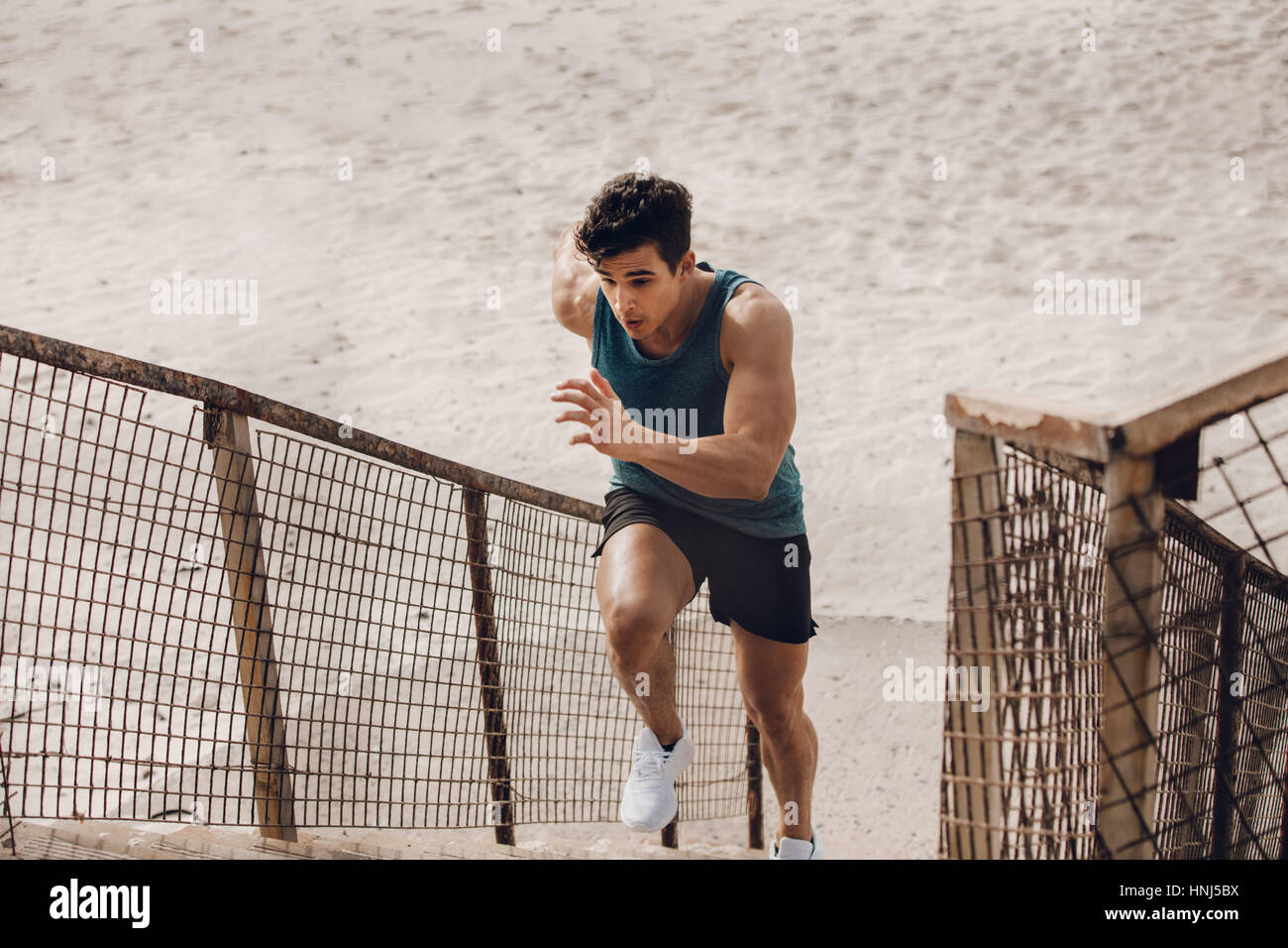 Passen Sie jungen Mann läuft die Stufen am Strand. Männliche Läufer trainieren am Strand. Stockfoto