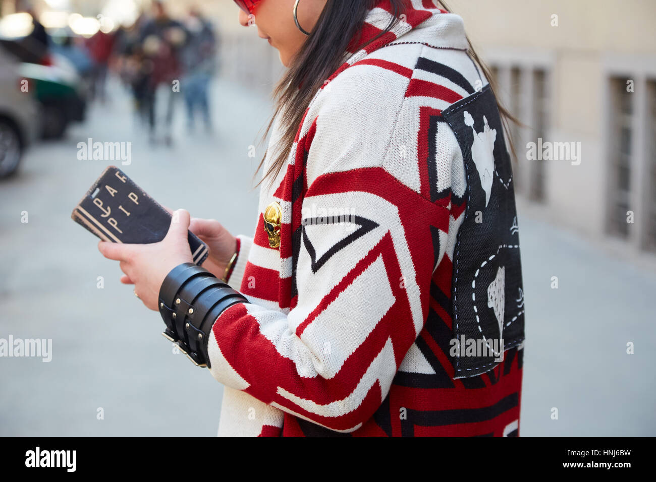 Mailand - Januar 16: Frau mit weißem und rotem Mantel mit geometrischen Design Blick auf Smartphone vor Cedric Charlier Modenschau, Mailand Fashion Week Stockfoto