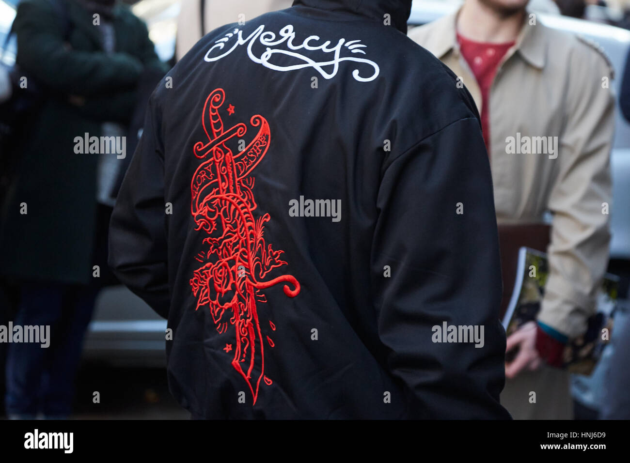 Mailand - Januar 16: Mann mit schwarzen Jacke mit Gnade schreiben und Schwert Design vor Cedric Charlier Modenschau, Milan Fashion Week Streetstyle auf Stockfoto