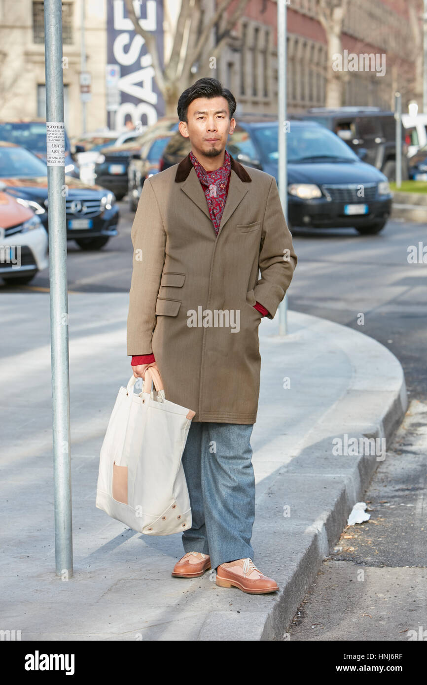 Elegante Mann mit braunen Mantel und rotem Schal vor Emporio Armani-Modenschau, Milan Fashion Week Streetstyle am 14. Januar 2017 Stockfoto