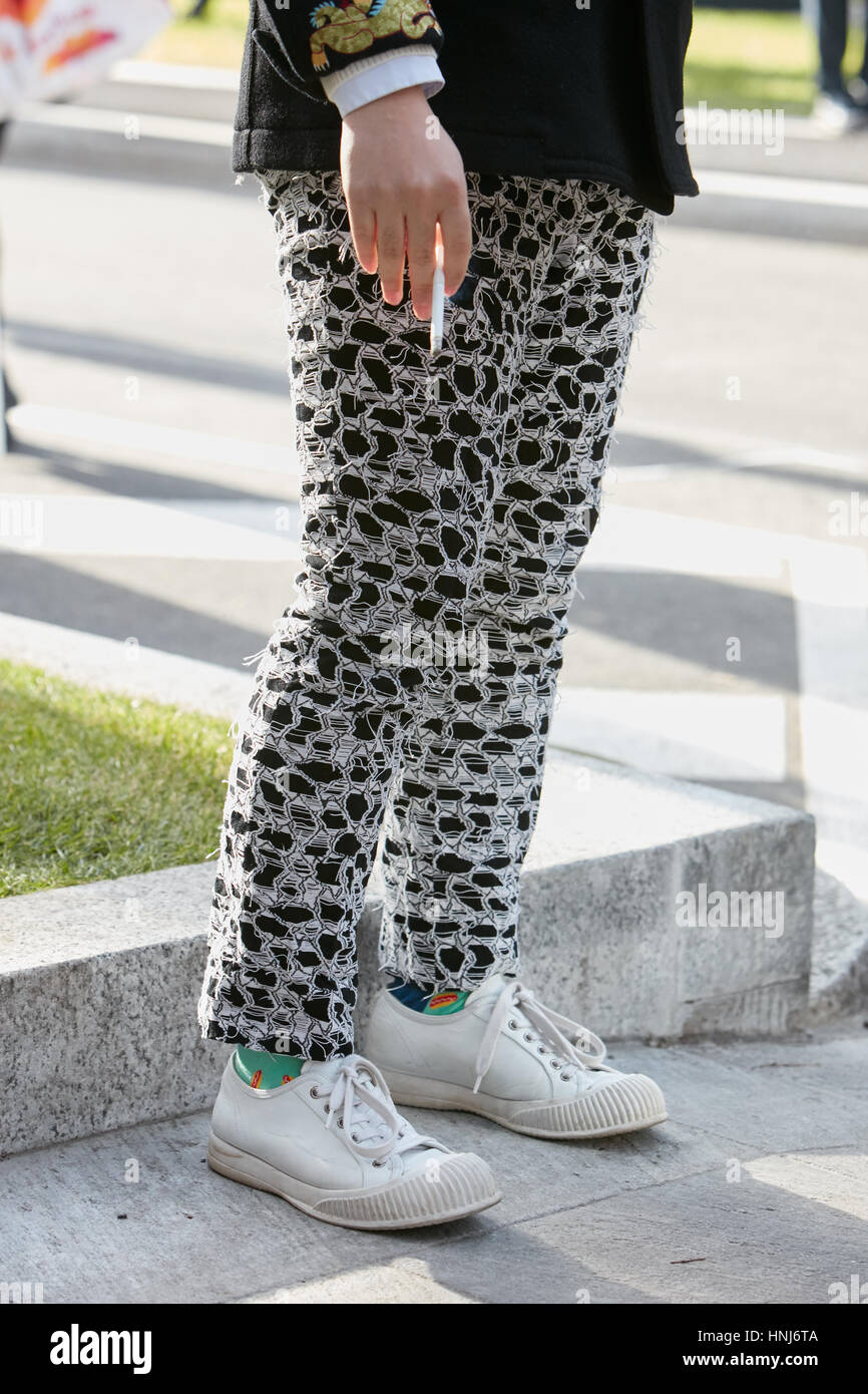 Mann mit schwarzen und weißen zerrissenen Hosen und weiße Schuhe vor Emporio Armani-Modenschau, Milan Fashion Week Streetstyle am Januar Stockfoto