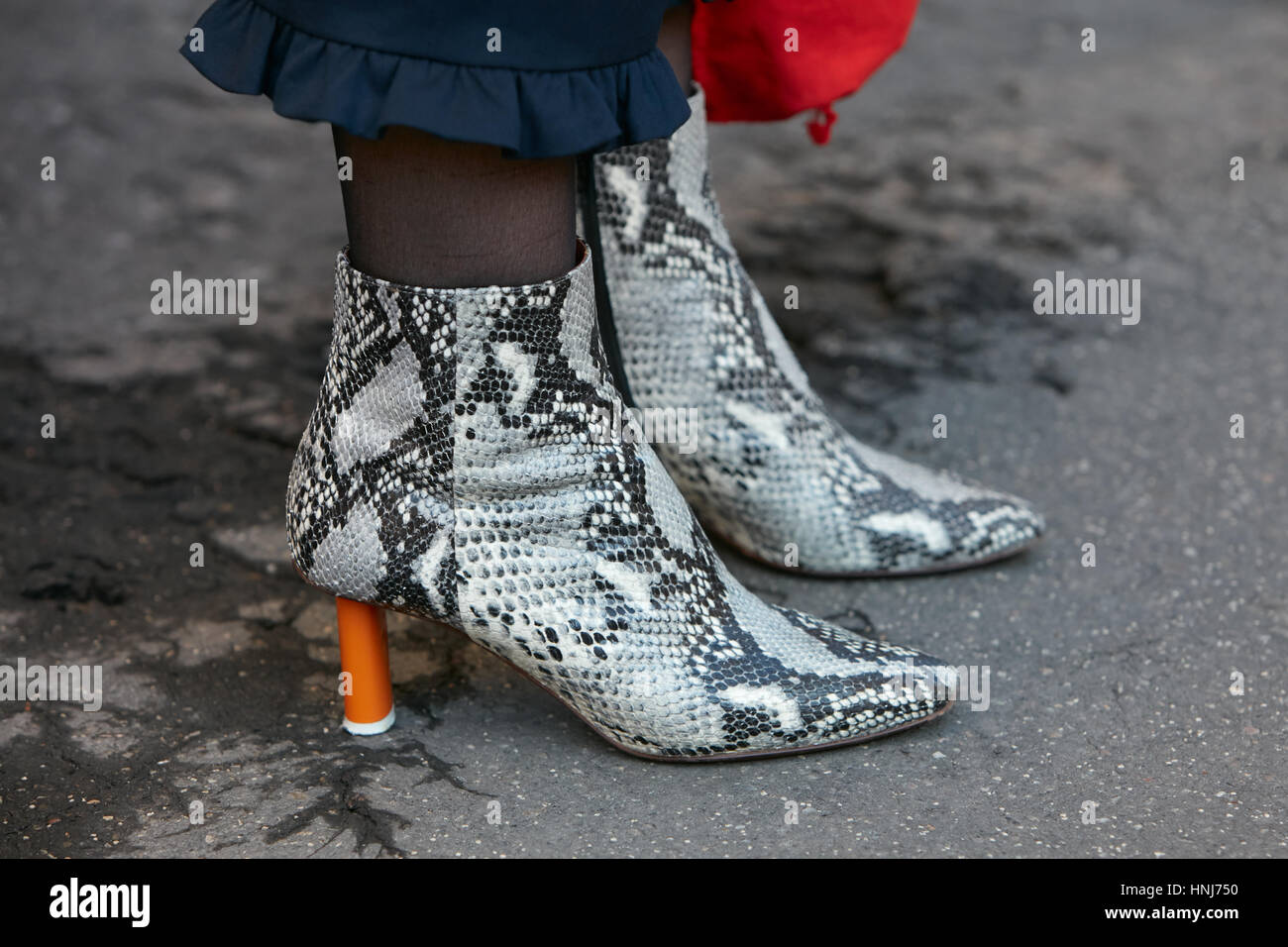 Frau mit schwarzen und weißen Schlange Stiefel mit orange Ferse, bevor Salvatore Ferragamo Modenschau, Milan Fashion Week Streetstyle. Stockfoto