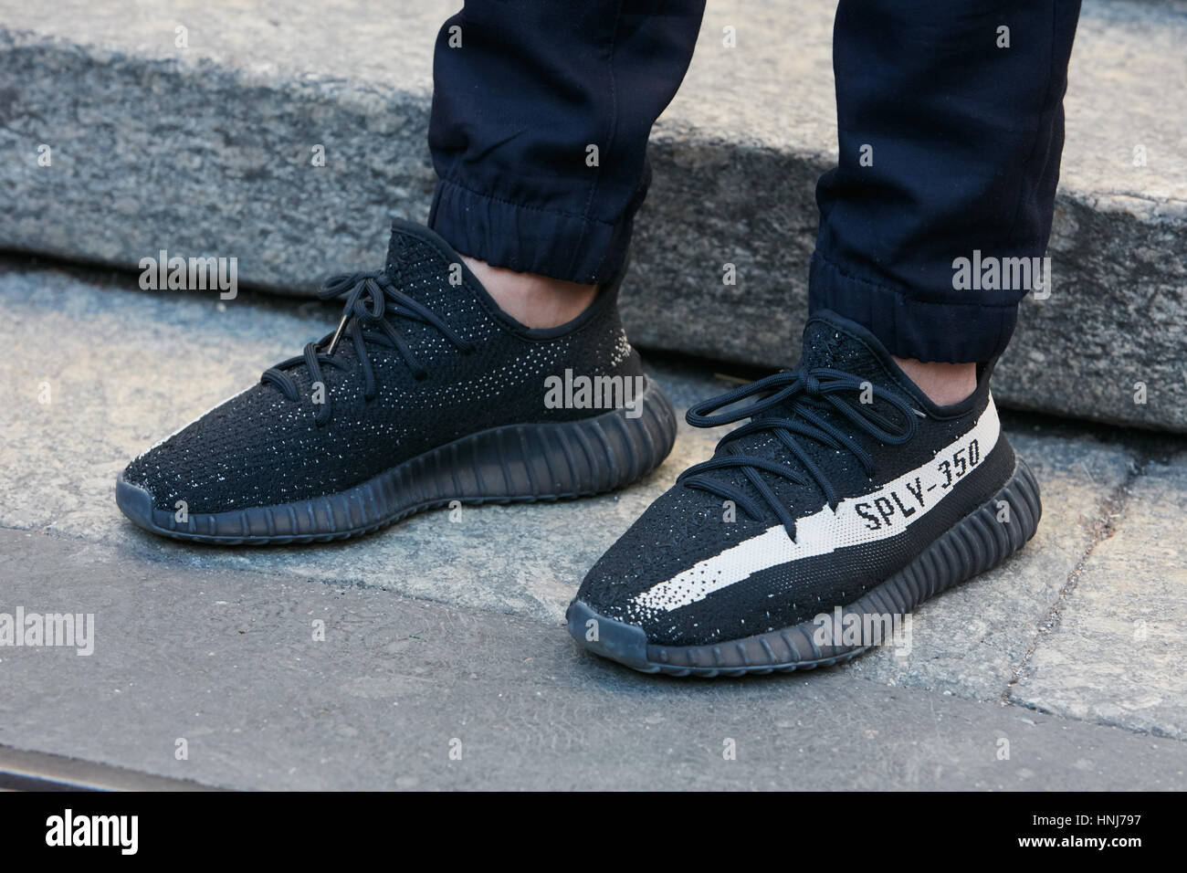 Mann mit Adidas Yeezy Boost 350 Schwarz Schuhe vor Salvatore Ferragamo Modenschau, Milan Fashion Week Streetstyle am 15. Januar 2017. Stockfoto