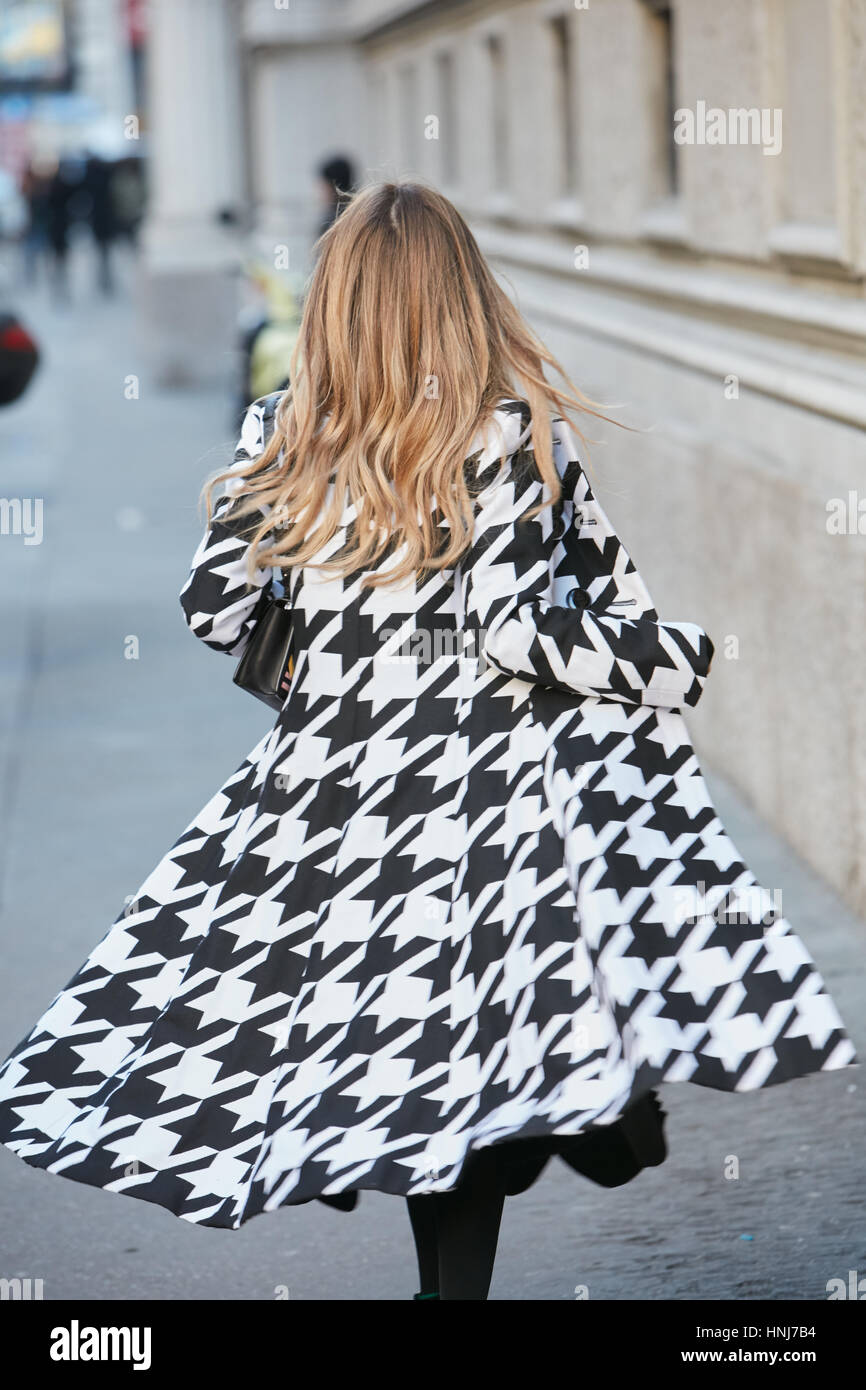 Frau mit schwarzen und weißen pied de Poule Mantel Wandern bevor Salvatore Ferragamo Modenschau, Milan Fashion Week Streetstyle am Januar 2017. Stockfoto