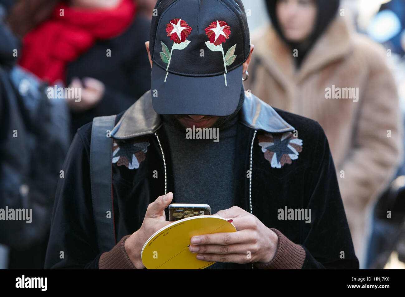 Mann mit schwarze Kappe mit roten Blumen Smartphone vor N 21 Modenschau, Milan Fashion Week Streetstyle am 16. Januar 2017 zu betrachten. Stockfoto