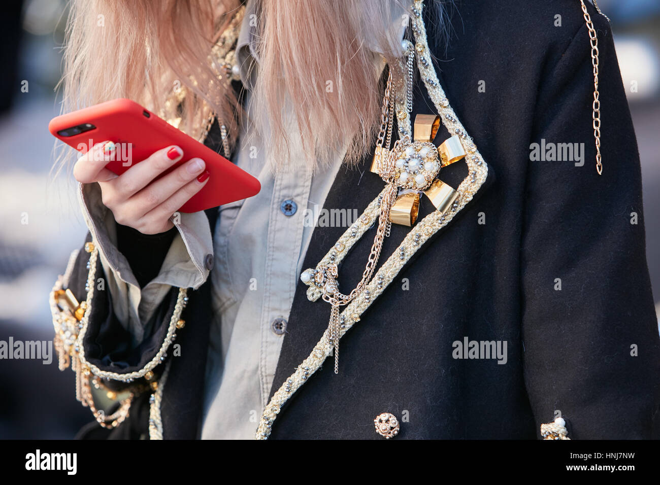 Frau schwarzer Mantel mit Goldene Ehrennadel, Dekorationen und rote Smartphone Cover bevor Etro Modenschau, Milan Fashion Week Streetstyle. Stockfoto