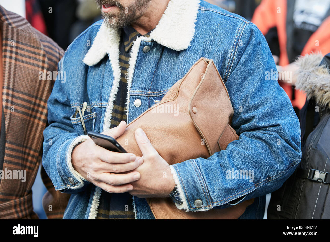 Mann mit Jeansjacke mit weißem Fell und braune Ledertasche vor MSGM Modenschau, Milan Fashion Week Streetstyle am 16. Januar 2017. Stockfoto