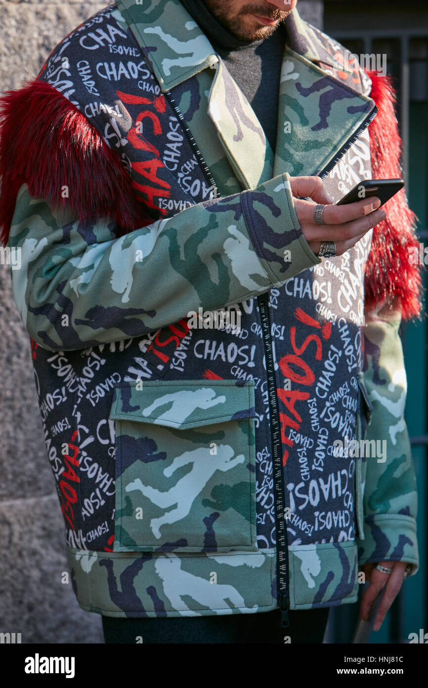 Mann mit Mantel mit Chaos schreiben und rotem Fell vor Giorgio Armani-Modenschau, Milan Fashion Week Streetstyle am 17. Januar 2017. Stockfoto