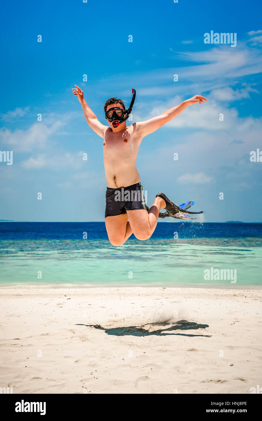 Lustiger Mann springt in Flossen und Maske. Urlaub an einem tropischen Strand auf den Malediven Inseln. Stockfoto
