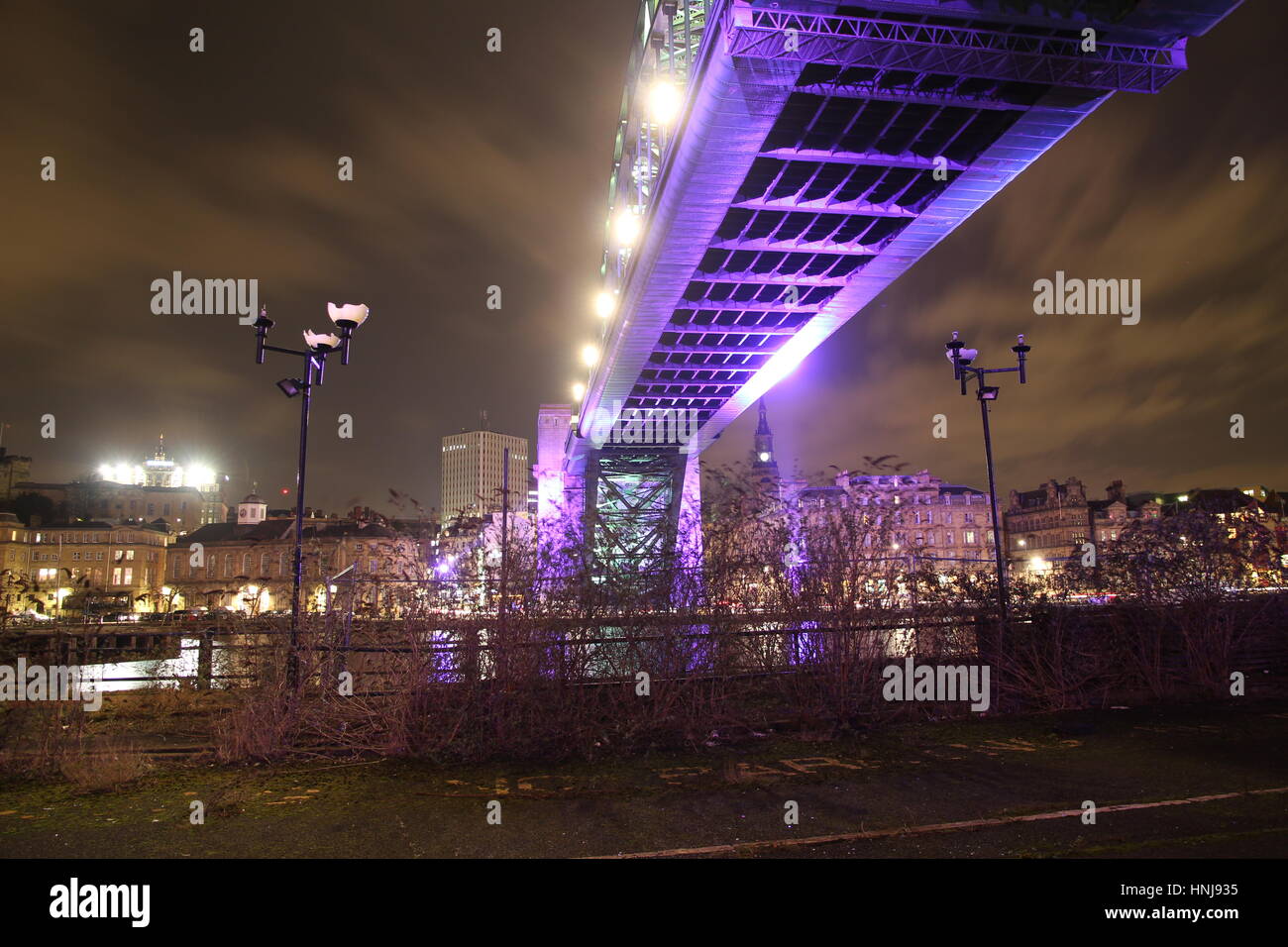 Seitlich und unten Ansicht von Newcastle Tyne Bridge mit einem Vordergrund zeigt eine fast dystopischen wirkenden Szene von defekten Straßenlampen und Unkraut Stockfoto