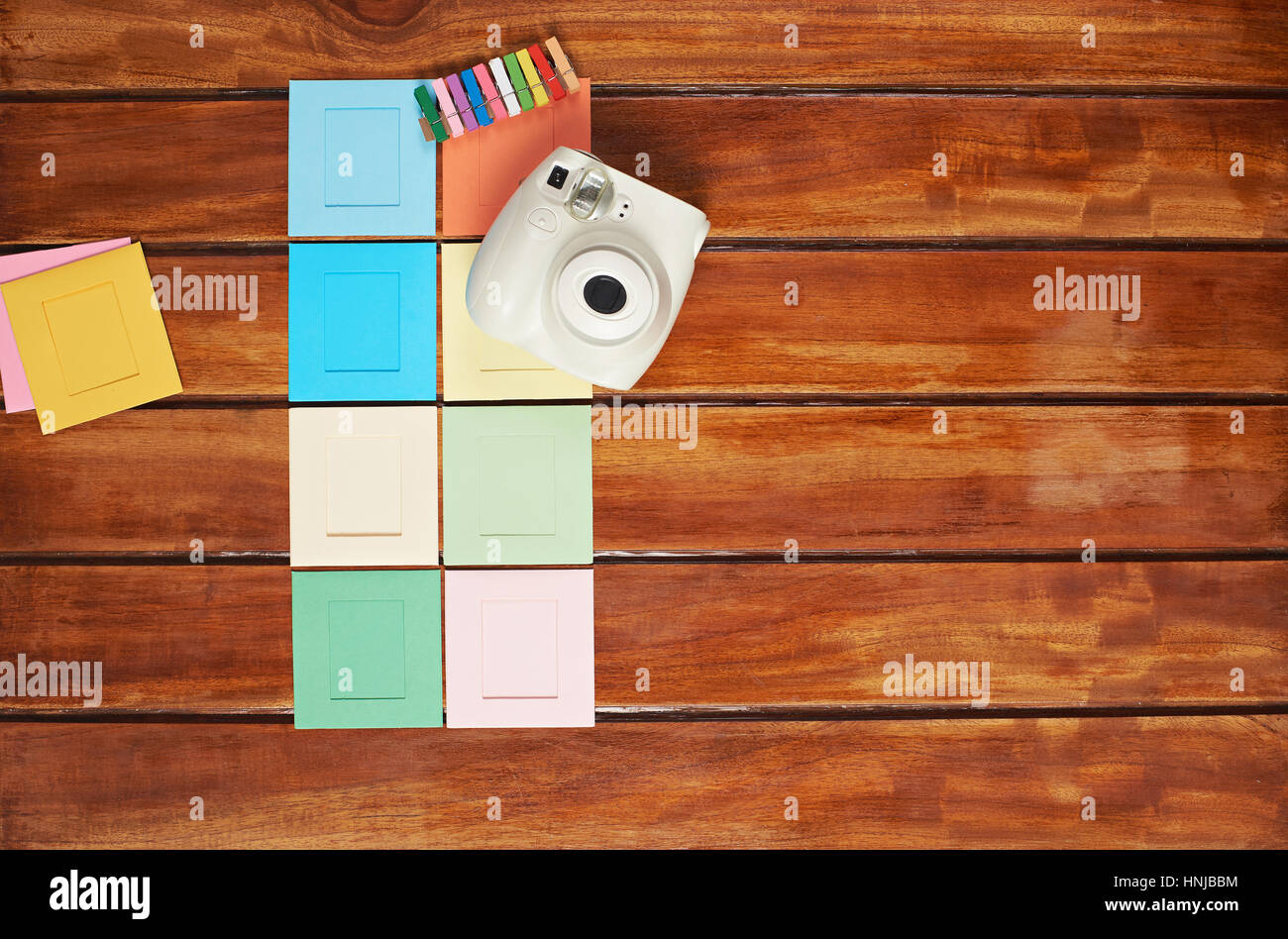 Sofortbild-Kamera mit bunten Bildern auf Holztisch mit leeren Textfreiraum Stockfoto