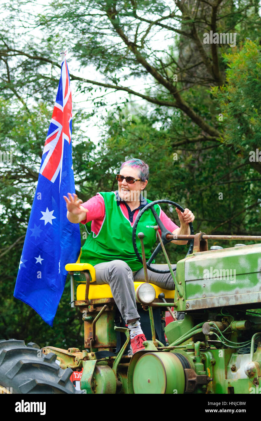 Eine Multi-Colour dunkelhaarige Frau einen Traktor zu fahren und winken beteiligt sich an der Australia Day 2017 Parade, Berrima, New-South.Wales, Australien Stockfoto