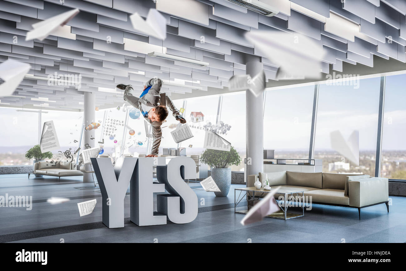 Fröhliche Jungunternehmer tanzen in seinem Büro. Mixed-media Stockfoto