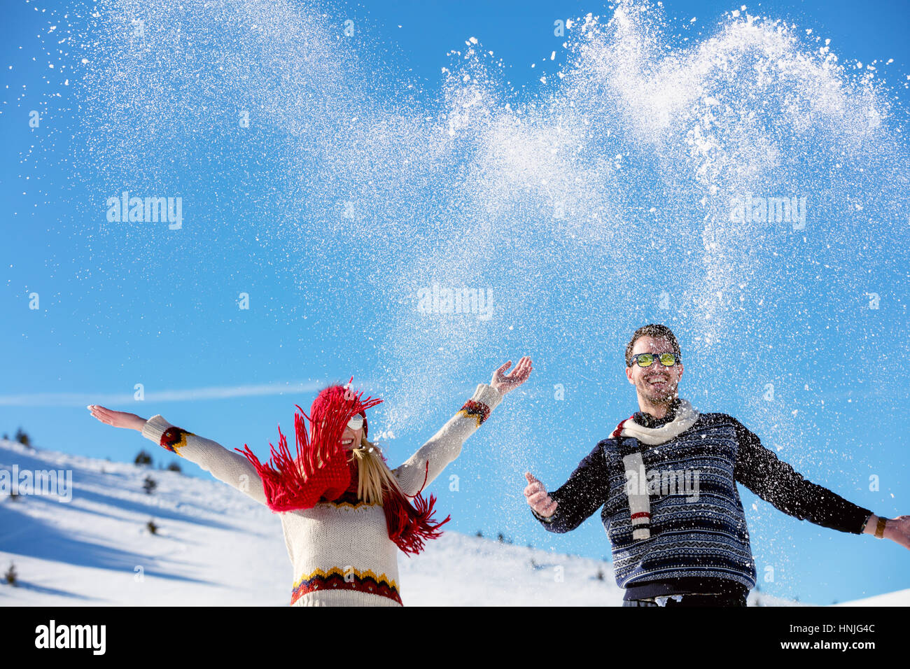 Schneeballschlacht. Winter-Paare, die Spaß im Schnee im Freien spielen. Junge fröhliche multiethnische Brautpaar. Stockfoto