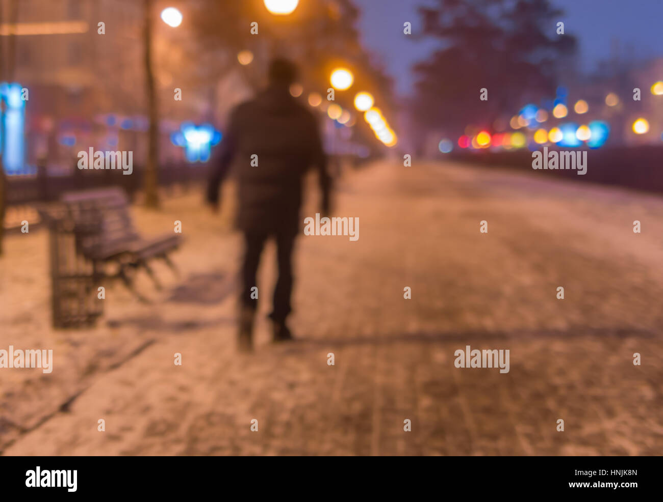 Unscharfen Hintergrund - Landschaft mit einsamen Mann zu Fuß auf einer leeren beleuchtete Straße in der Nacht im Wintersaison Stockfoto