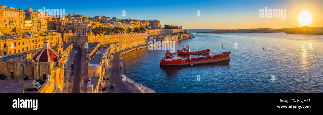 Valletta, Malta - Panorama Skyline Blick auf Valletta und den Grand Harbour mit wunderschönen Sonnenaufgang, Schiffe und klaren, blauen Himmel Stockfoto