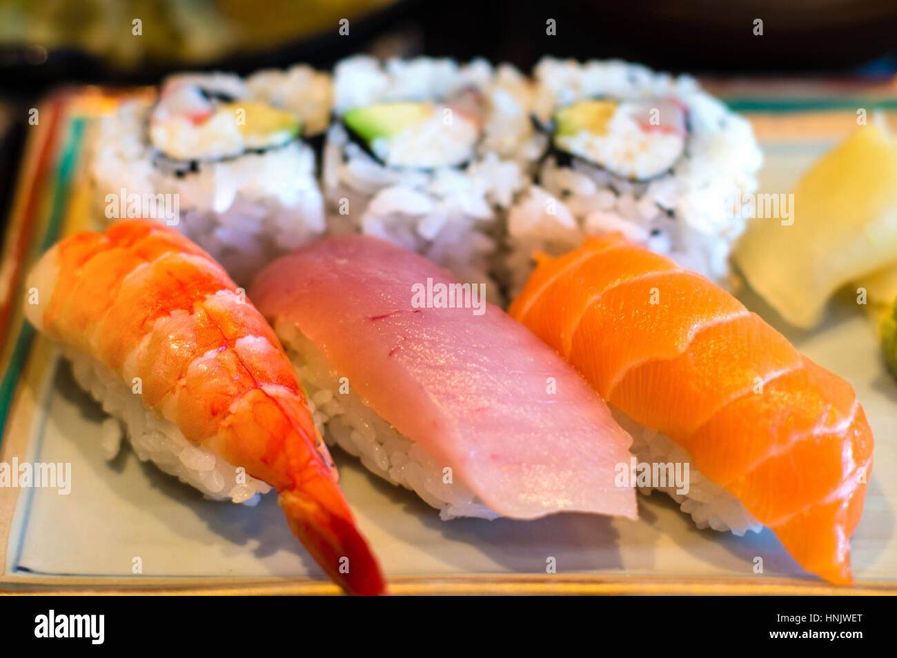 Nahaufnahme des japanischen Nigiri Reis Sushi Platte mit Ebi (Garnelen) Sushi, Maguro (Thunfisch) Sushi und Sake (Lachs) Sushi mit California-Rollen in der ba Stockfoto