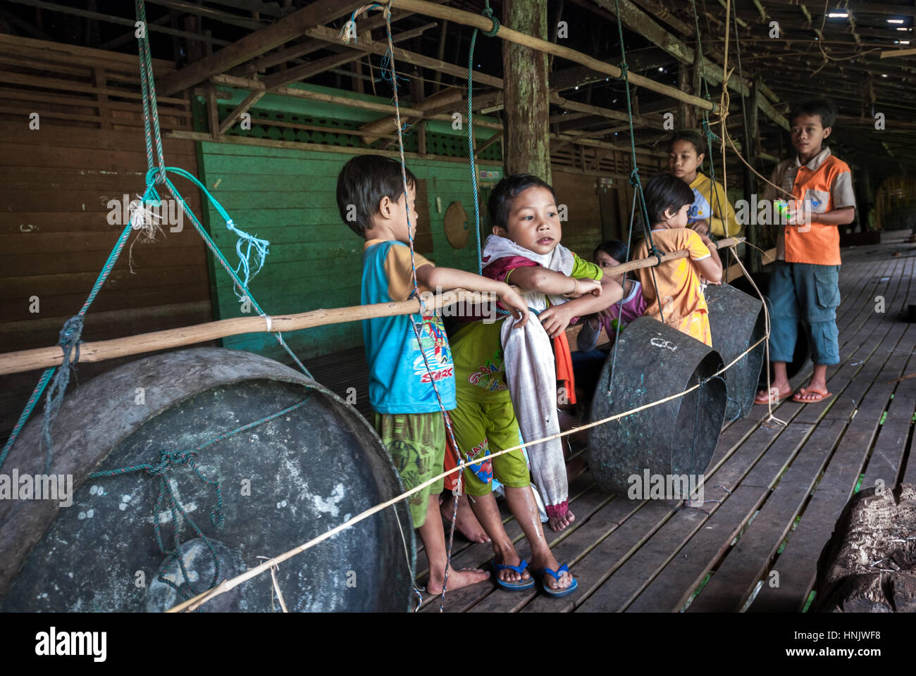 Kinder spielen in der Nähe von Gongs (traditionelle Percussion) im Longhouse von Uluk Palin in West Kalimantan, Indonesien. Stockfoto