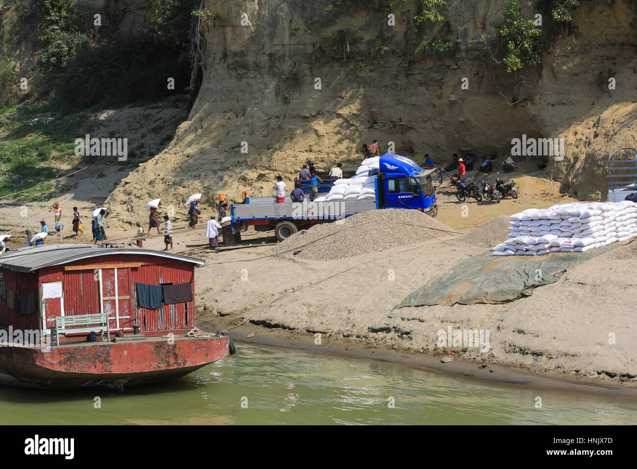 Männer und Frauen Arbeiter sind Laden Säcke aus einer Ladung Boot zu einem Lkw an den Ufern des Irrawaddy Flusses in Myanmar (Burma). Stockfoto