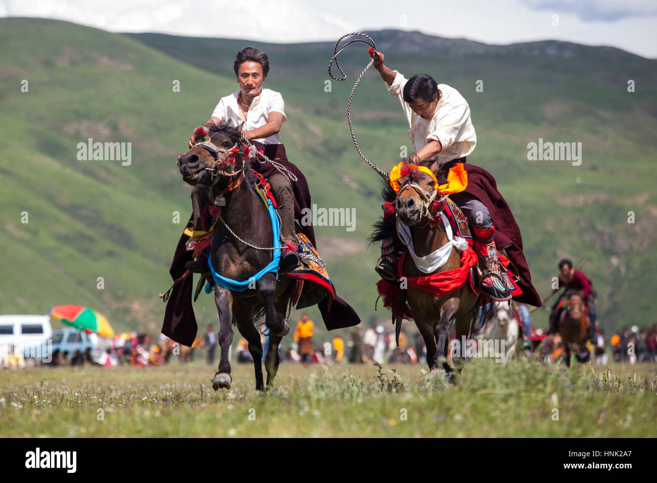 Khampa Männer auf Pferden reiten, während die Manigango Pferdefest in der tibetischen Hochebene in Sichuan, China. Stockfoto