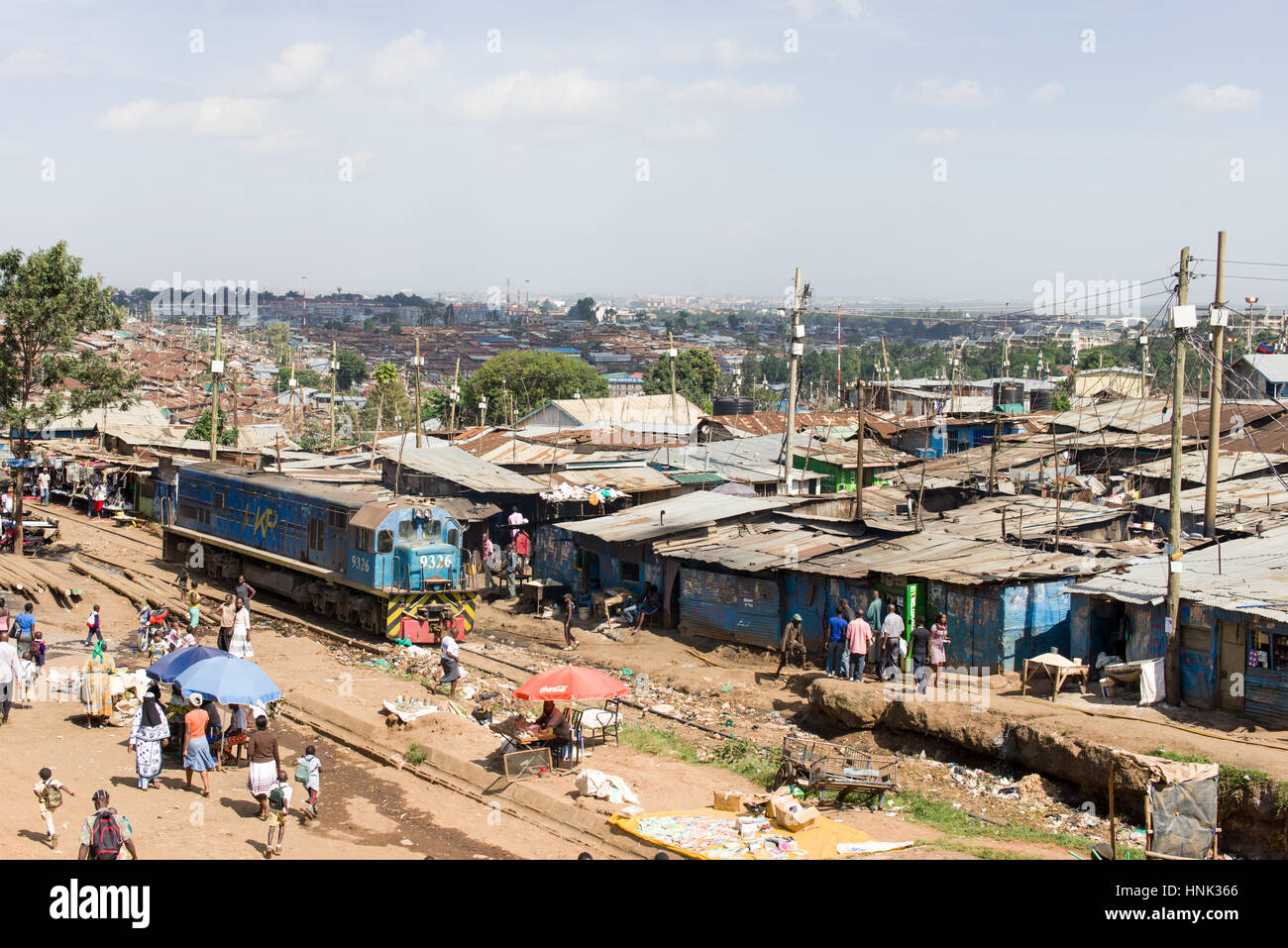 Ein Zug Lokomotive fährt durch Slum Kibera als Bewohner gehen über das tägliche Leben, Nairobi, Kenia Stockfoto