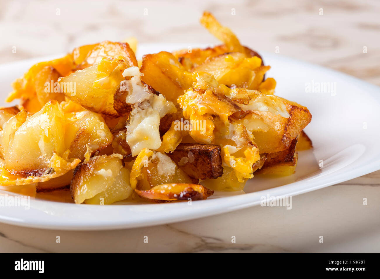 Pommes Frites mit zerschlagenen Eiern auf weißen Teller über Tisch Stockfoto