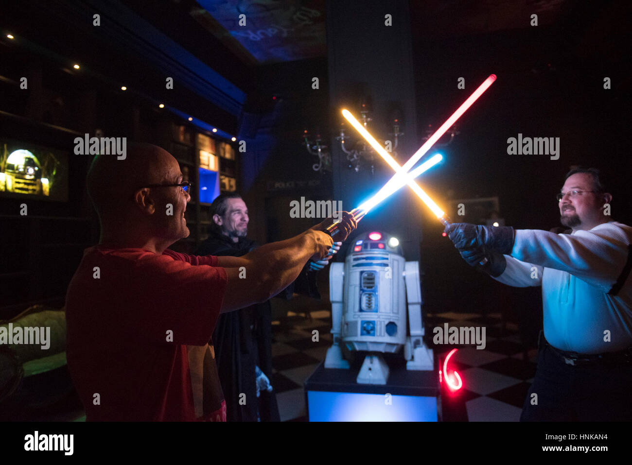 Alex Pusineri, Besitzer der Millenniums-Fandom Bar, links, Steven See, Zentrum und Gabriel Colbaugh zeigen ihre Lichtschwerter während einer Star Wars Party. Stockfoto