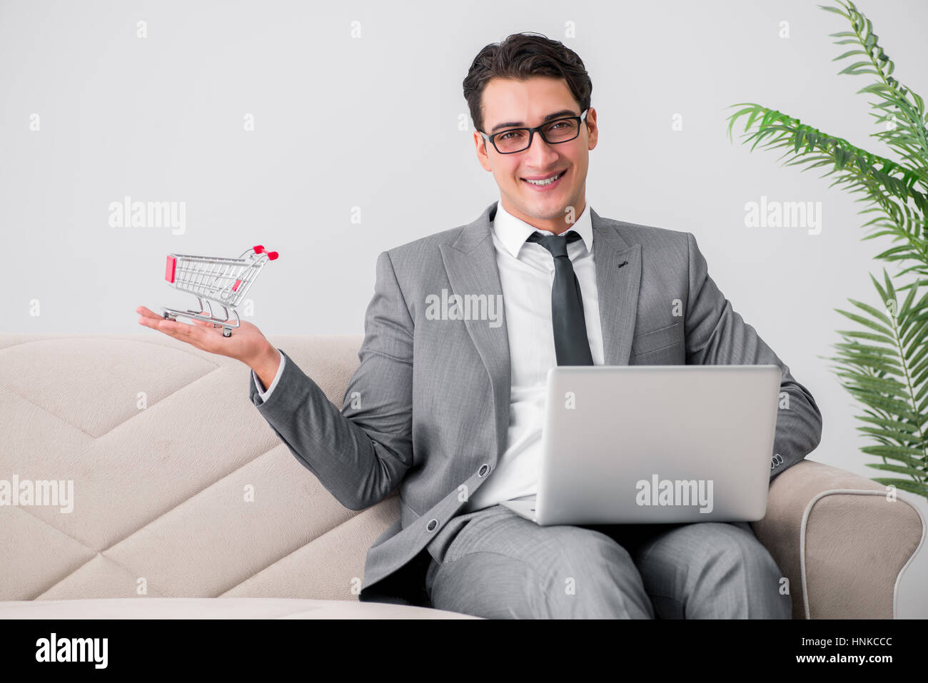 Geschäftsmann mit Laptop und Warenkorb Stockfoto