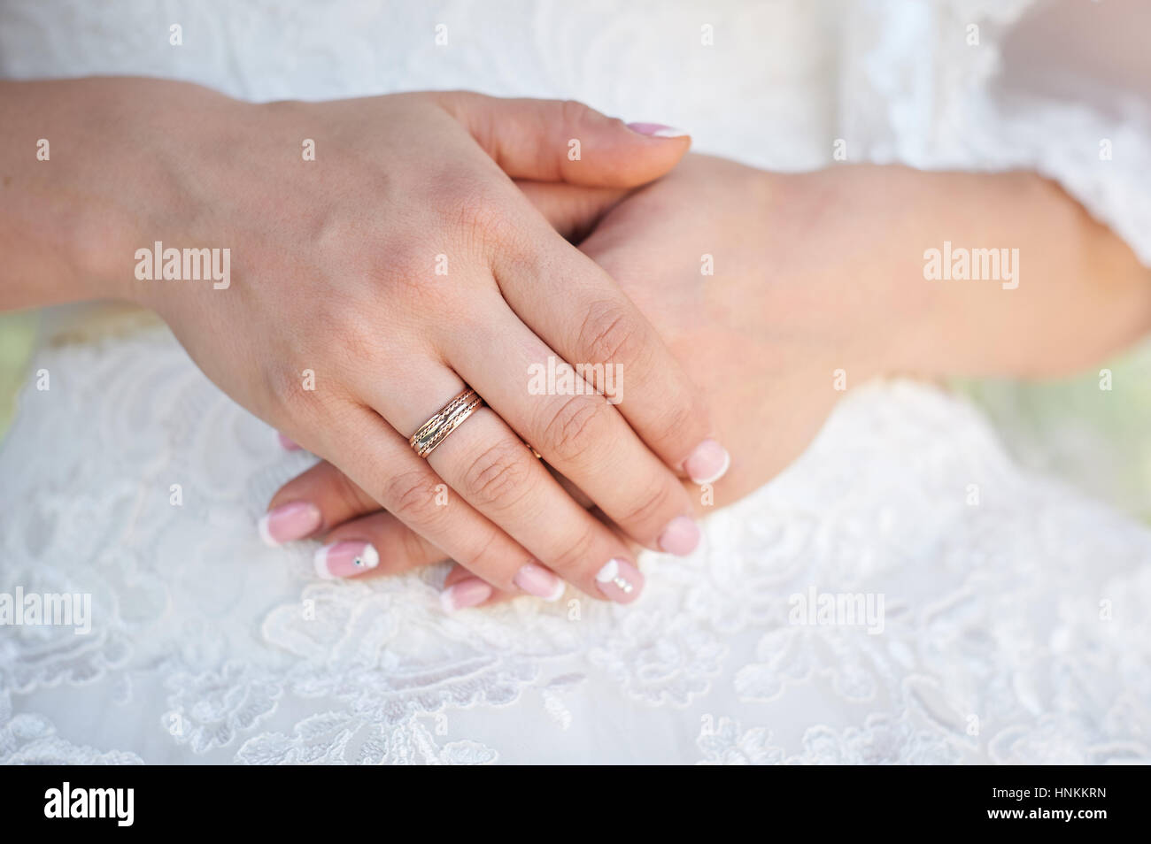 Hand der Braut mit einem Ehering auf dem Hintergrund des Kleides Stockfoto