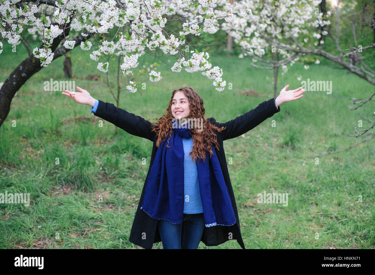 schöne glückliche junge Frau, die zu Fuß in einer blühenden Frühlingsgarten Stockfoto