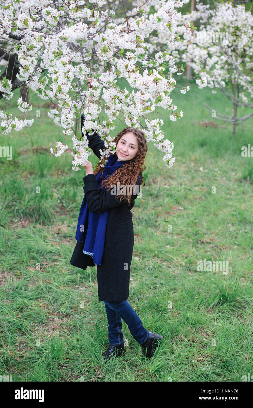 schöne glückliche junge Frau, die zu Fuß in einer blühenden Frühlingsgarten Stockfoto