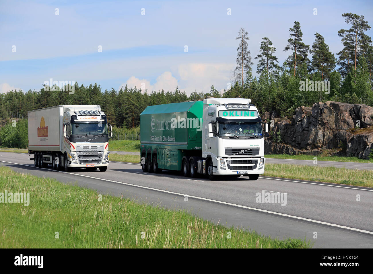PAIMIO, Finnland - 3. Juni 2016: Volvo FH OKline Semi Trailer Flachglas-Transport-Anhänger überholt ein weiterer Volvo FH-Sattelschlepper auf Autobahn im Sommer. Stockfoto