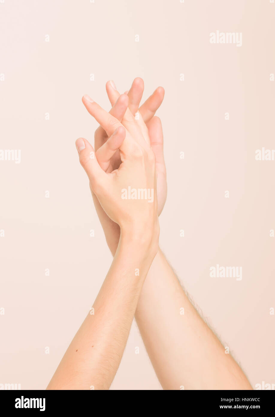 Hände von Mann und Frau zärtlich berühren einander auf gereinigte Haut Ton Hintergrund Stockfoto