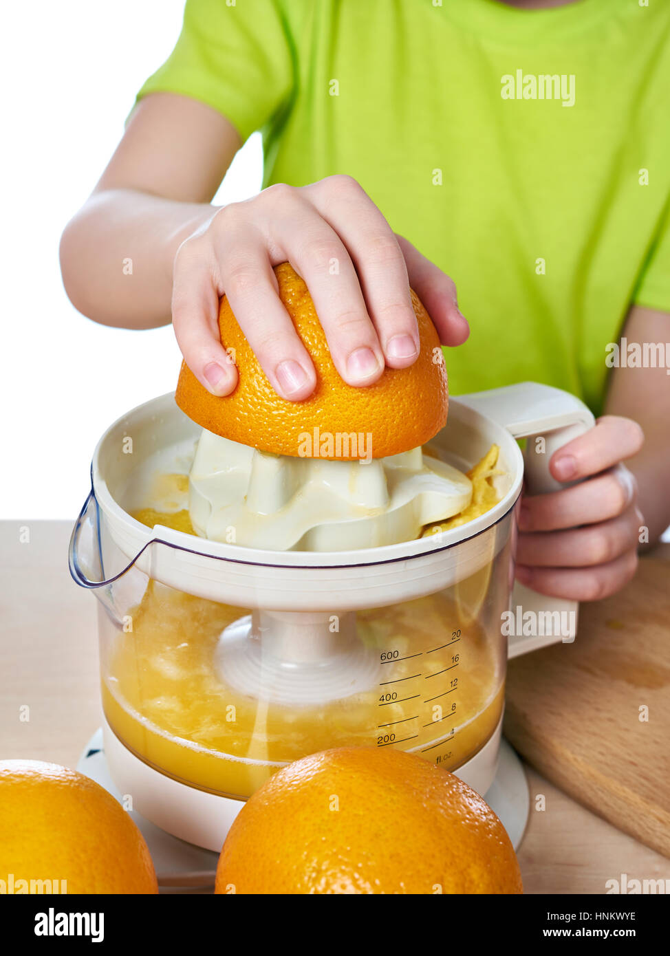 Junge mit Orangen macht den Saft in einen Entsafter isoliert weiß Stockfoto