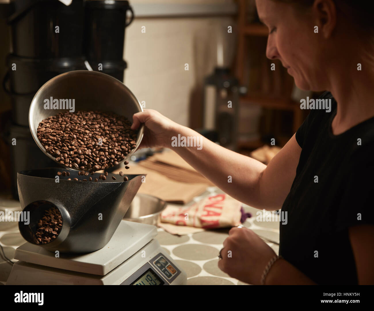 Ein Coffee-Shop. Eine Person Gießen geröstete Kaffeebohnen in eine Kaffeemühle. Stockfoto
