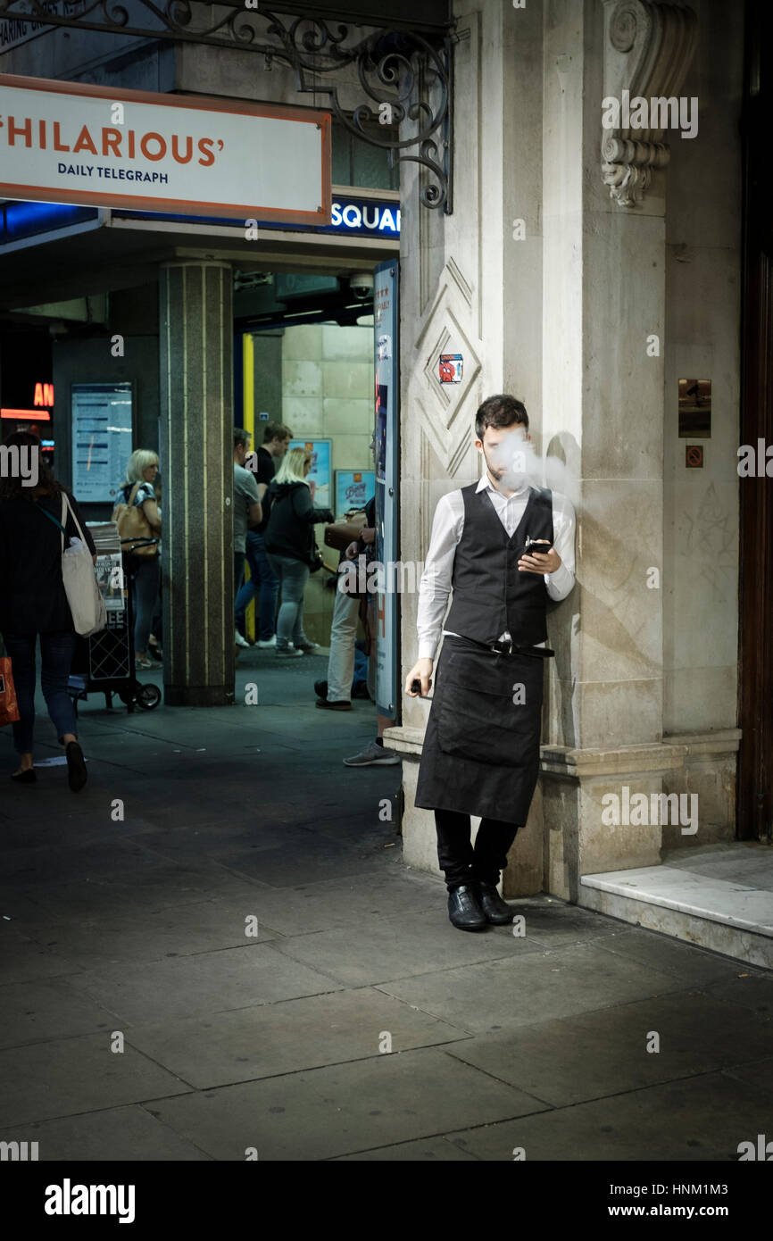 Kellner mit Zigarettenpause, Leicester Square u-Bahnstation, Londom, UK Stockfoto