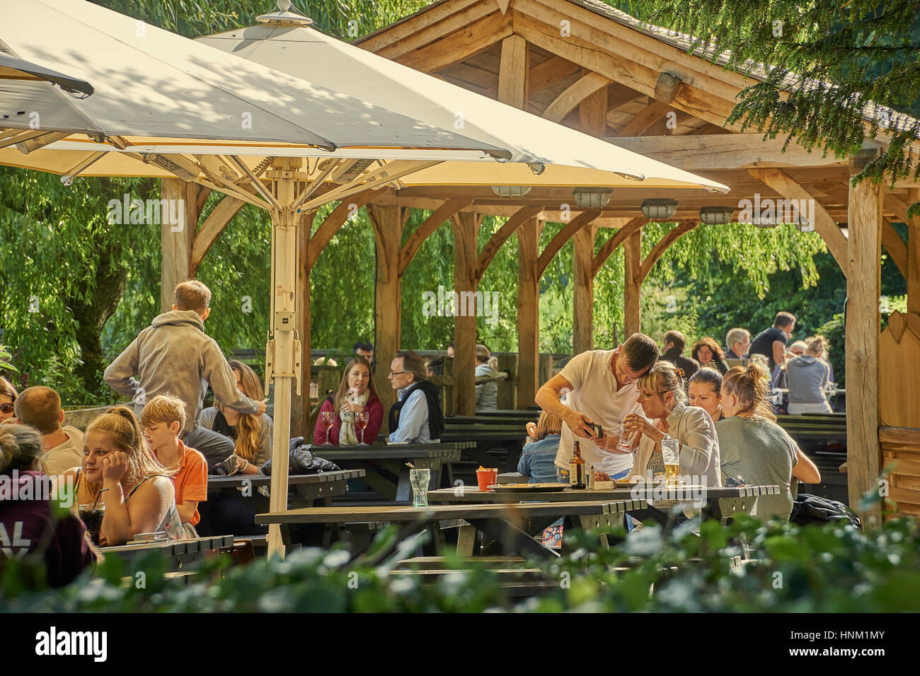 Menschen Essen im Freien ein Café mit Sonnenschirmen an einem Sommertag Stockfoto