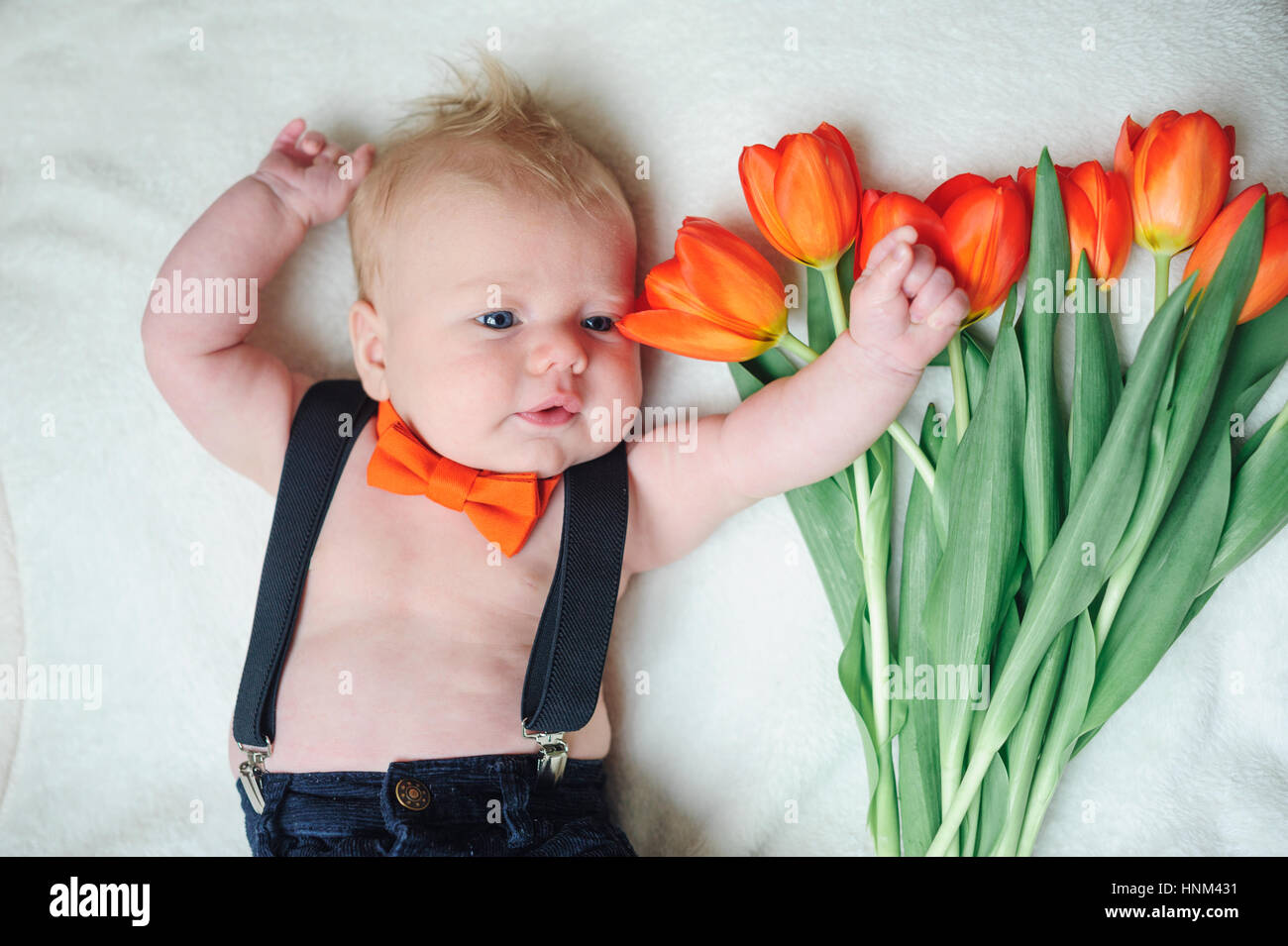 schönes kleines Baby liegen in der Nähe von Tulpen Stockfoto